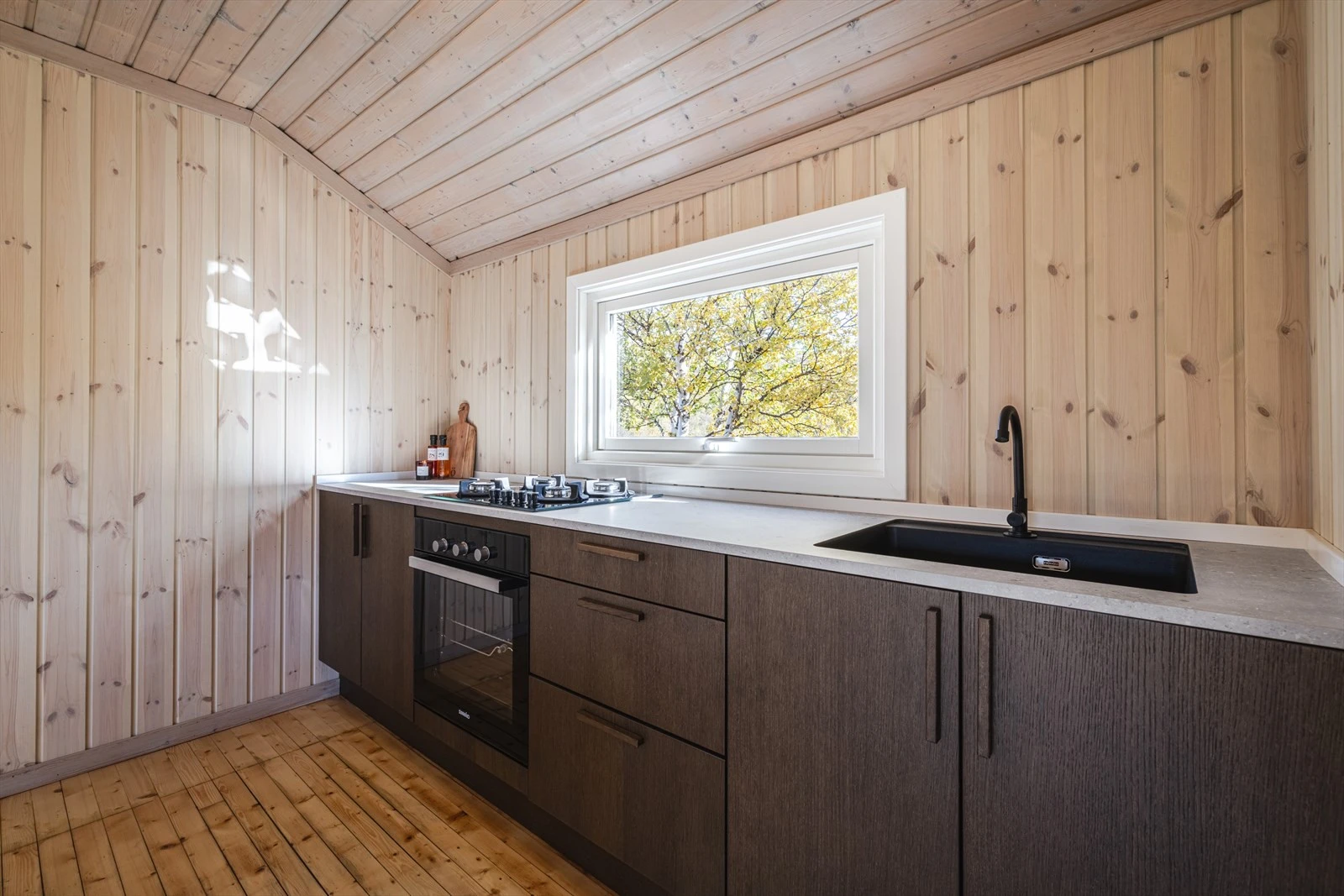 Ny kjøkkeninnredning med utslagsvask og kran som kobles til dunk. Det er og ny gasskomfyr og steketopp Galleribilde