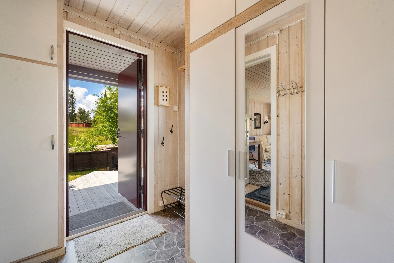 Når du kommer inn i hytta via inngangspartiet, møtes du av et praktisk vindfang med garderobeskap i folierte plater og speildører Galleribilde