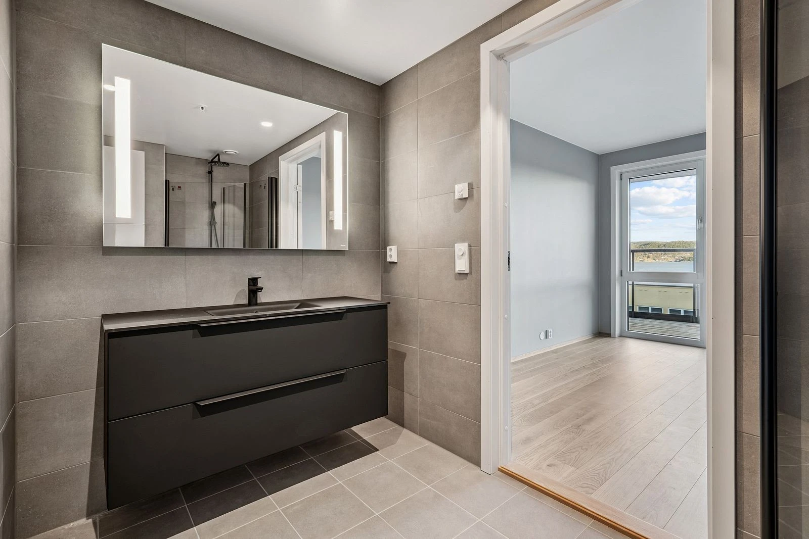 Flislagte og moderne bad som gir spa-følelse i hverdagen med utgang til hovedsoverommet.