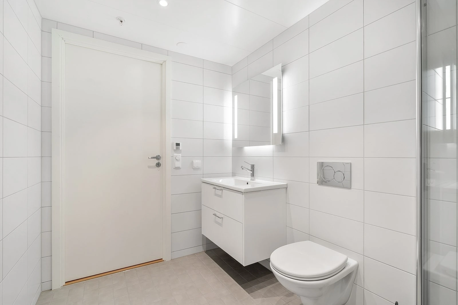 Badet leveres med hvit servant montert i benkeplate med underskap, samt speil med integrert lysarmatur over vasken for et praktisk og elegant preg.