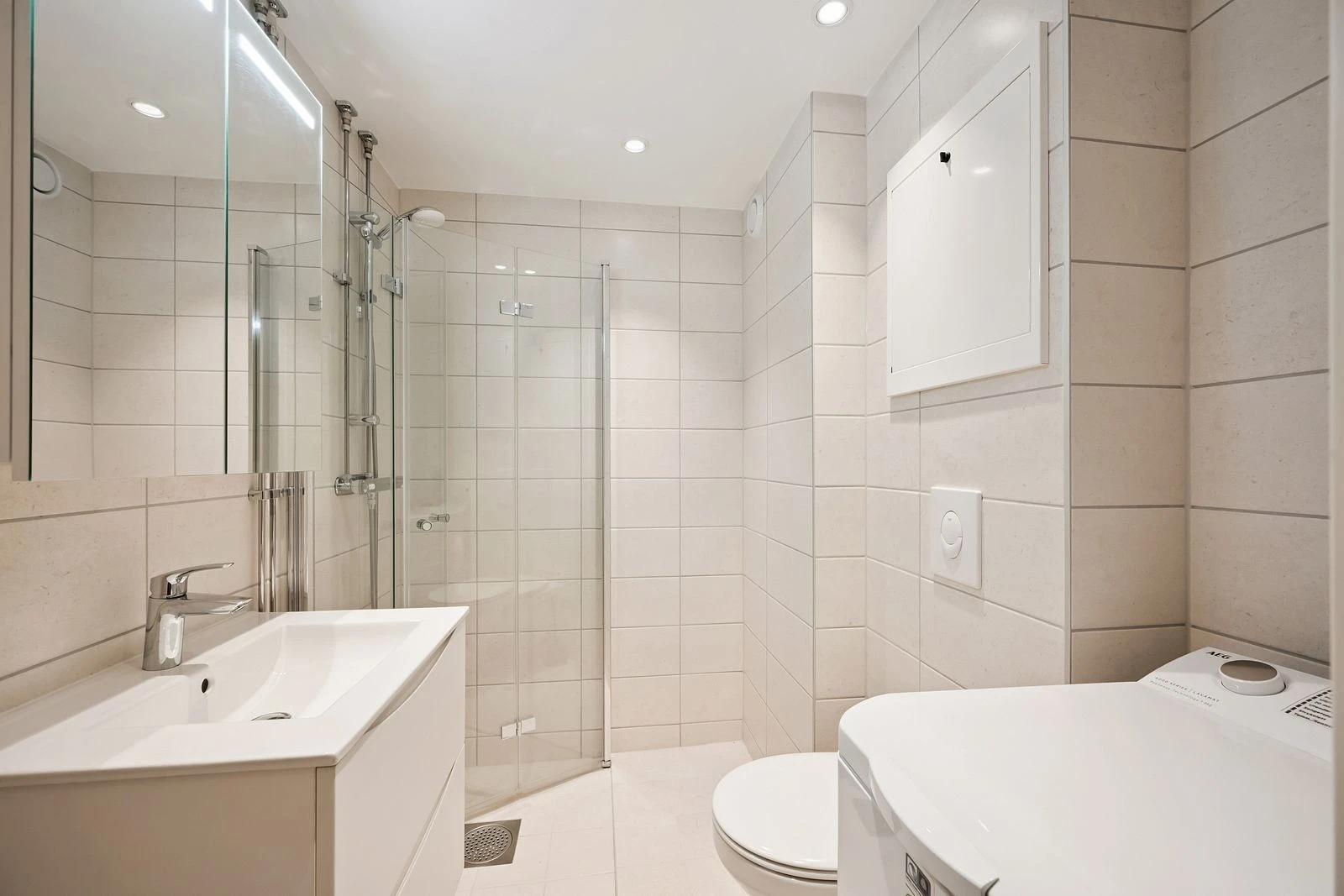 Moderne baderomsinnredning med funksjonell lagringsplass og spotlights.