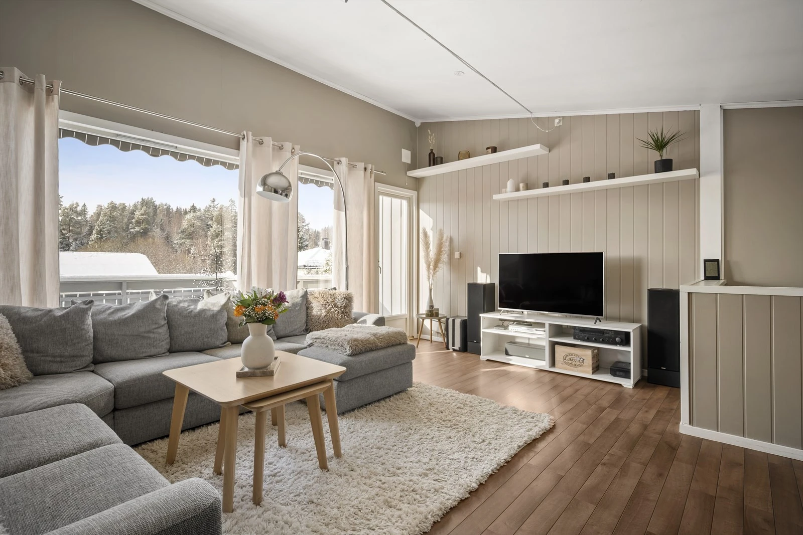 En lys og pen stue med store vinduer.