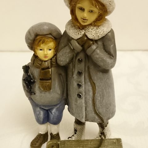 Søt liten figur av gutt og jente med kjelke - kunstmateriale