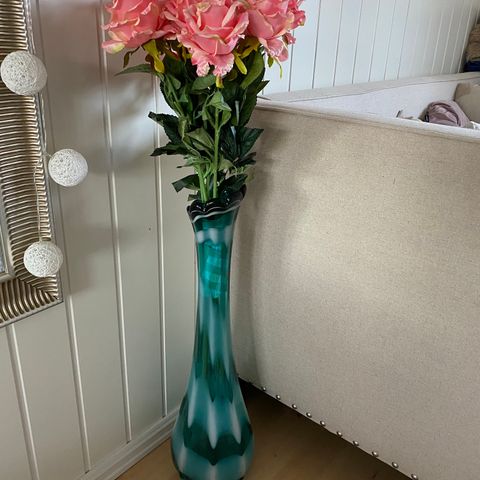 En høy nydelig vase med kunstig blomster