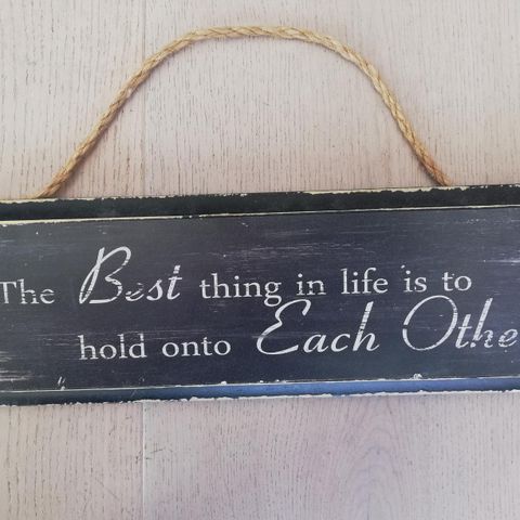 Tøft treskilt med tekst: 'The Best thing in life is to hold onto Each Other'