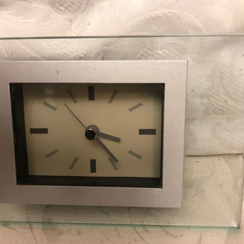 Fin liten klokke , i glass og stål. ca. 16 x 11 cm.