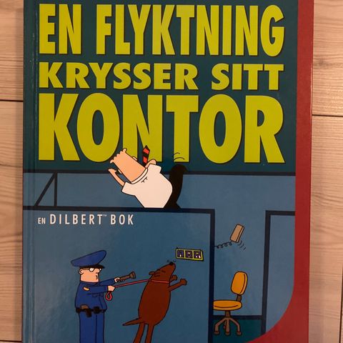 En flyktning krysser sitt kontor. En Dilbert bok. Tegneseriebok