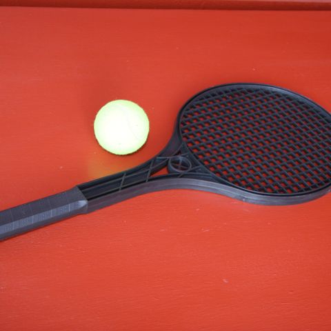 En sort racket + en gul tennis ball