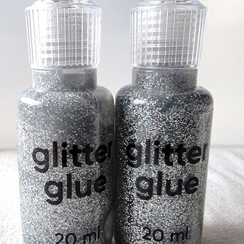 To flasker med glitterlim i glitrende grått