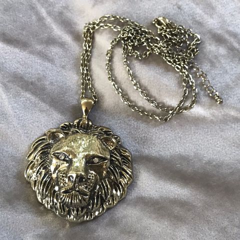 Løvesmykke gullfarget metall med strassøyne 7cm kjede 86cm