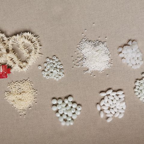 Et sortiment av hvite glass og korallperler for å lage smykke