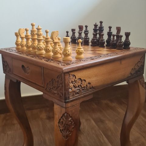 Håndlaget sjakkbord med brikker