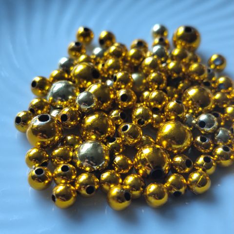 Gullfargede perler i ulike størrelser