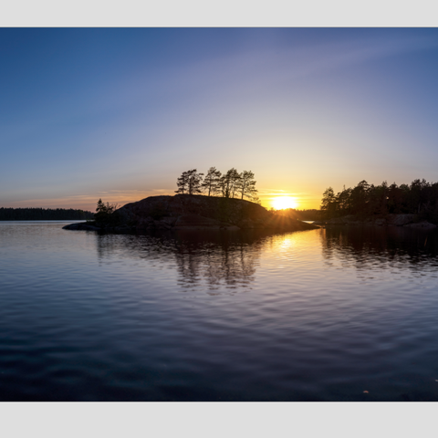 Stort fotografi av solnedgang bak rundeholmen Vansjø