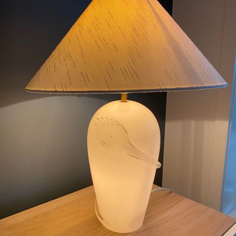 Bordlampe med lys inni hvit lampefot