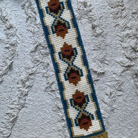 Smal vintage stramei brodert veggteppe med tradisjonelt mønster.