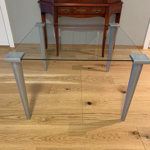 Glassbord med sølvfargede ben og hjørner