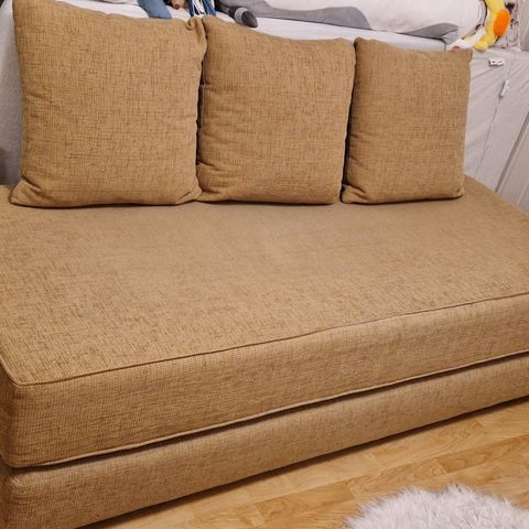 Sovesofa i beige farge med tre ryggputer