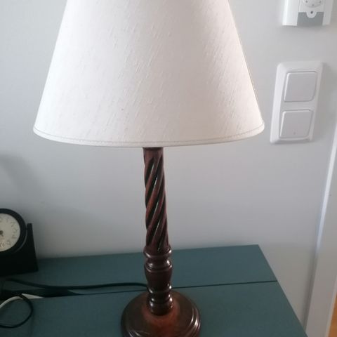 Pen brun lampe fot i tre, med hvit skjerm ca 50 cm høy.