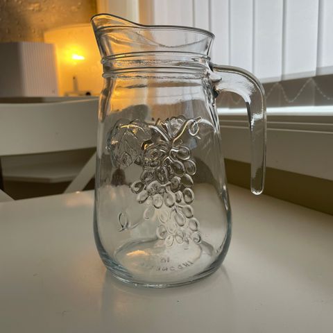 Vakker glassmugge med druer på