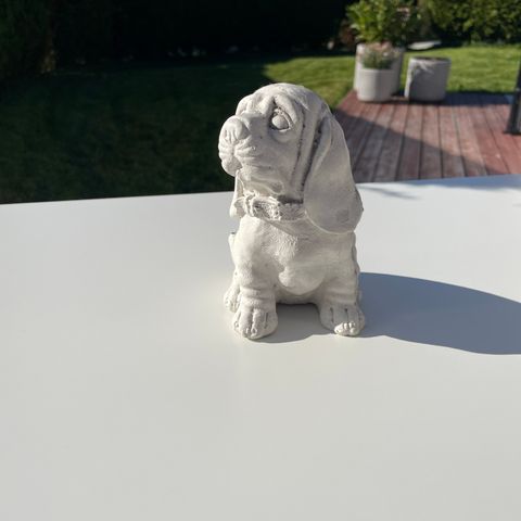 Fin liten hunde statue som tåler alt av vær.