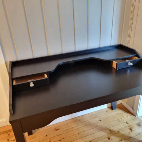 Svart IKEA skrivebord med hylle.