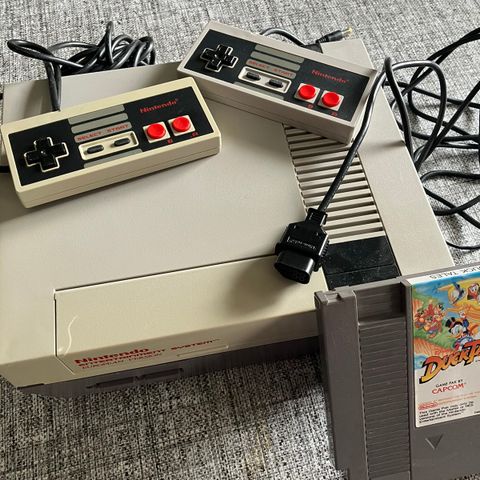 Nintendo nes maskin med to håndkontoller og ett spill.