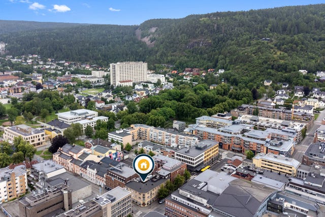 Dronefoto som viser plassering av eiendommen midt mellom Torget vest og elven