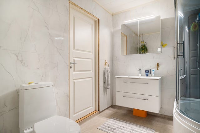 Badet er innredet med servant, toalett og dusjkabinett. Veggene har våtromsplater, gulvet er belagt med vinylbelegg, og rommet har elektrisk avtrekksvifte i himlingen.