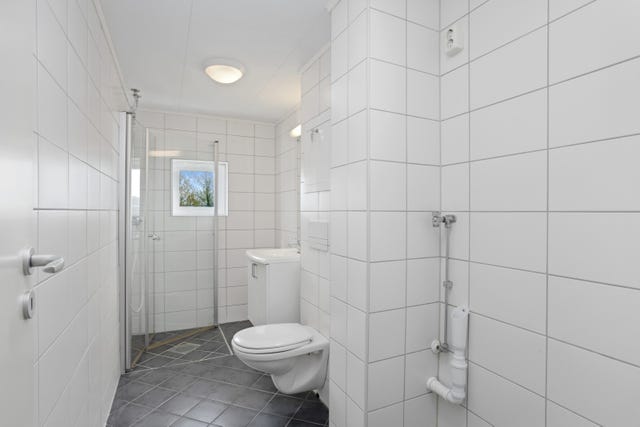 Badet er pent, lyst og flislagt med vegghengt toalett og plass til vaskemaskin.