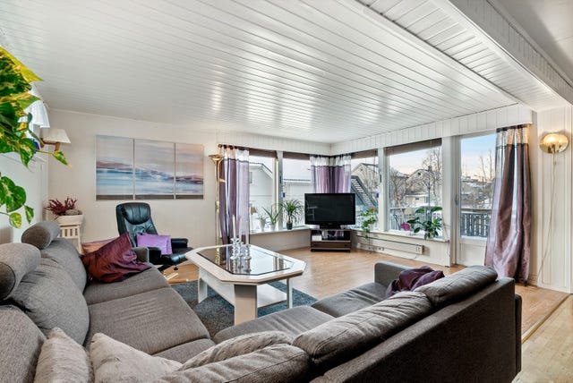 Store, åpne vindusflater og altandør som leder ut til veranda og hage.