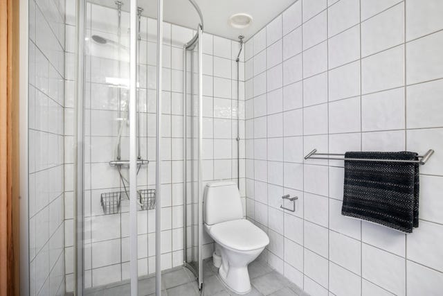 Pent, funksjonelt bad med flislagte vegger og gulv med varmekabler.