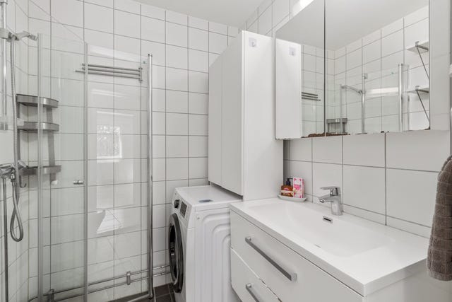 Flislagt bad med dusjnisje, vaskemaskin, vask og toalett