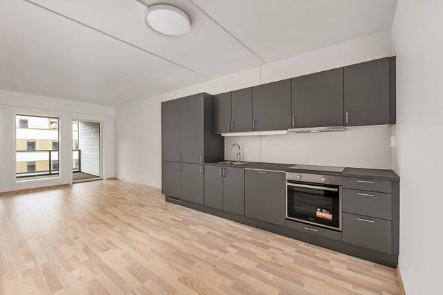 Kjøkkenet er av slette, sorte fronter og benkeplate med nedfelt oppvaskkum for et lekkert og gjennomført uttrykk.