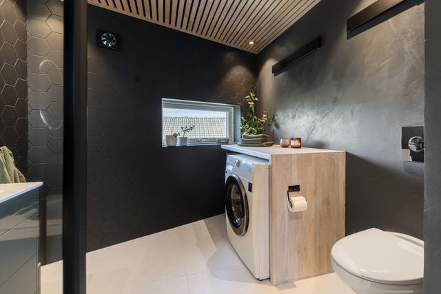 Badet er innredet med en praktisk vaskesone som gir god benkeplass og opplegg for vaskemaskin.
