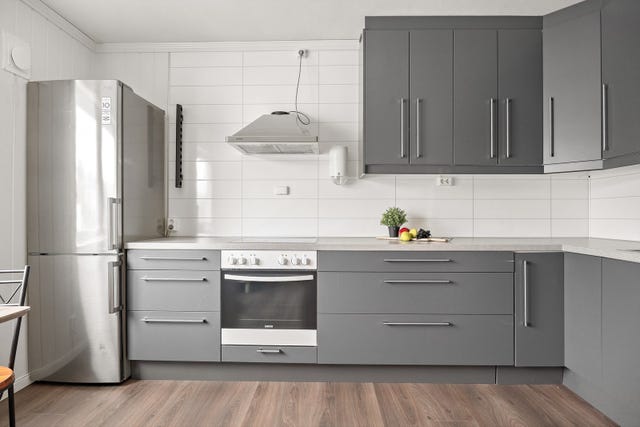 Kjøkkenet har innredning med glatte fronter og benkeplate av laminat. Det er montert kjøkkenplater på veggene mellom benkeplate og overskap. Over platetoppen er det kjøkkenventilator med kullfilter, og det er montert komfyrvakt på veggen.