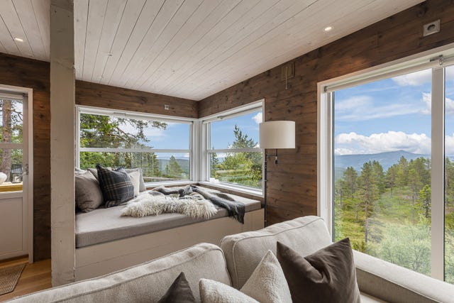 En lun daybed ved vinduene skaper et herlig sted for avslapning med naturen tett på.