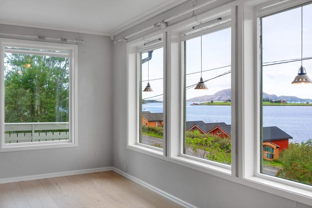 De store vinduene i stuen gir utsikt mot natur og sjø.