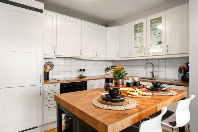 Innredningen har lyse, profilerte fronter kombinert med laminert benkeplate og flislagt vegg mellom benkeplate og overskap. Det er godt med skap- og arbeidsplass, og den praktiske kjøkkenøya gir både oppbevaringsplass og større arbeidsflate.