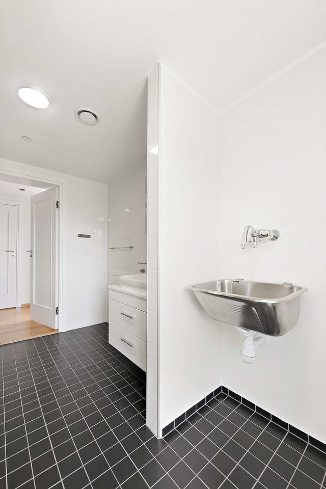 Vaskeromsdelen er utstyrt med skyllekar og opplegg for vaskemaskin mens badet er utstyrt med baderomsinnredning, toalett og dusjveggerhjørne.