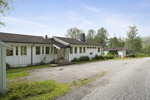 Tomten er terrassert over flere nivå. Mot vei er et plant nivå med gode parkeringsmuligheter både foran hus og garasjene.