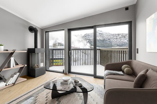 Stuen har gasspeis og skyvedør ut til en solrik balkong. Møblene er redigert inn.