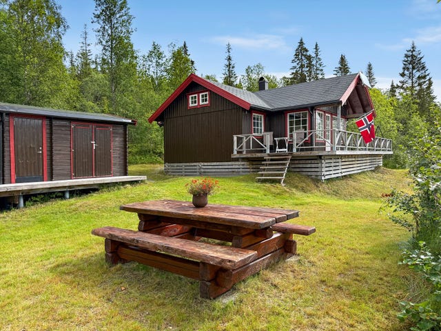 Eiendommen består av hovedhytta og et praktisk uthus i matchende farger, noe som skaper et veldig harmonisk og helhetlig tun.