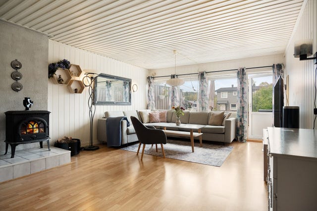 Lys og innbydende stue med vedovn som skaper en lun og hyggelig atmosfære.
