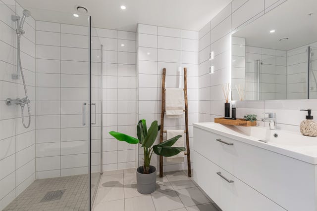 Romslig, flislagt bad/WC med dusjnisje, downlights og baderomsinnredning med rikelig oppbevaringsplass