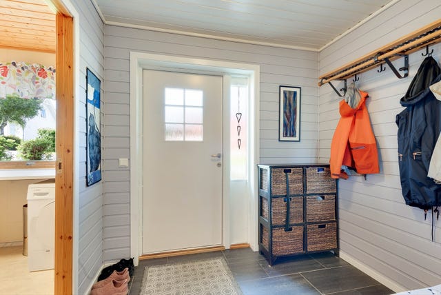 Vindfanget i første etasje, med flislagt gulv og oppheng for klær.