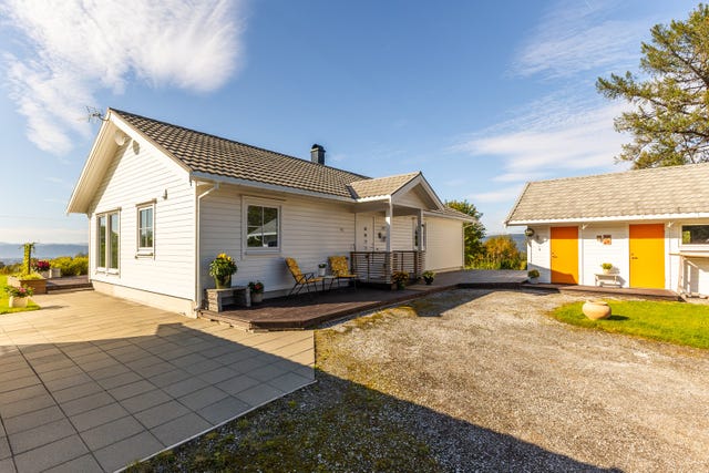Tomten rundt bebyggelsen er flat, lettstelt og pent opparbeidet med plen, terrasser, betongheller og gruset innkjørsel/gårdsplass.