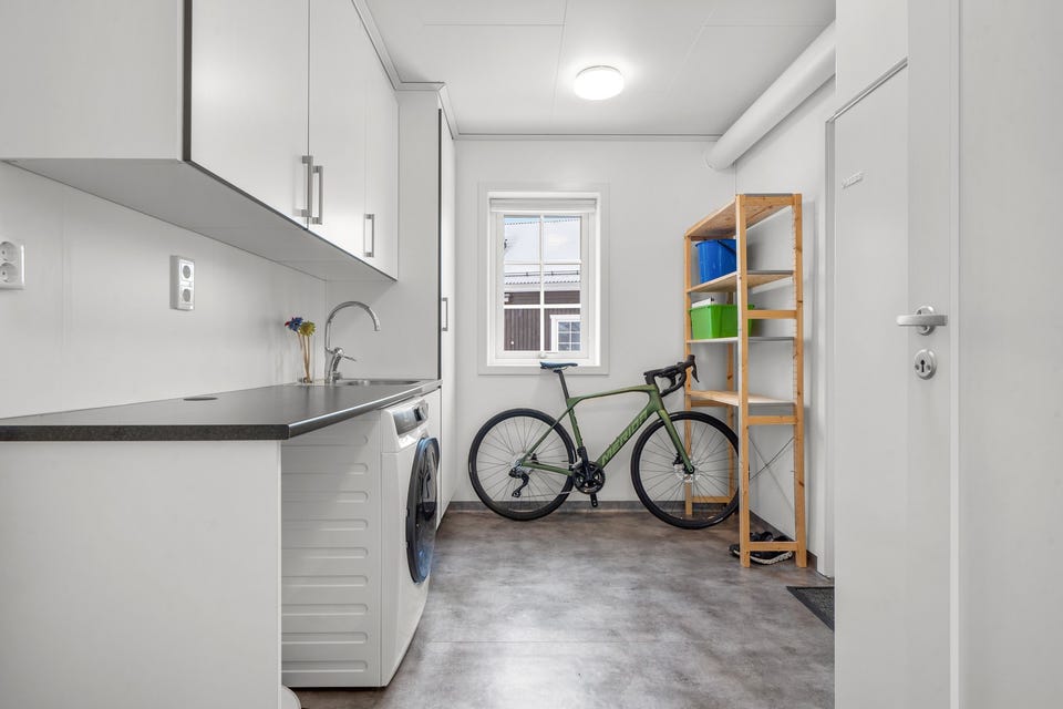Boligen har også et lyst og praktisk vaskerom med belegg på gulv, lyse overflater og mekanisk avtrekk.