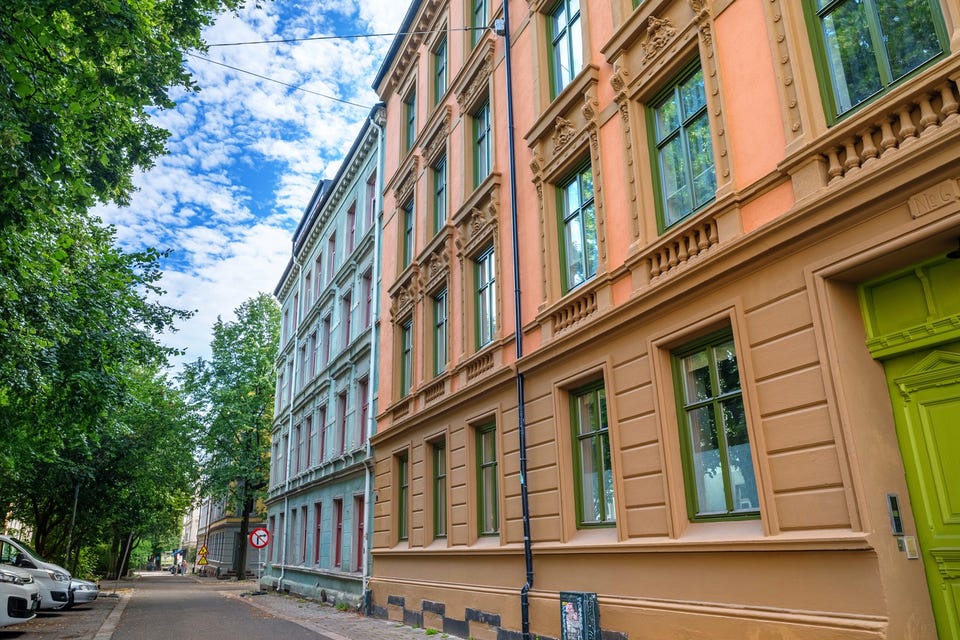 Gatefasade med dekorative vindusomramminger og grønt inngangsparti. Bygården er fra 1898; leilighetens vinduer vender kun mot bakgården.