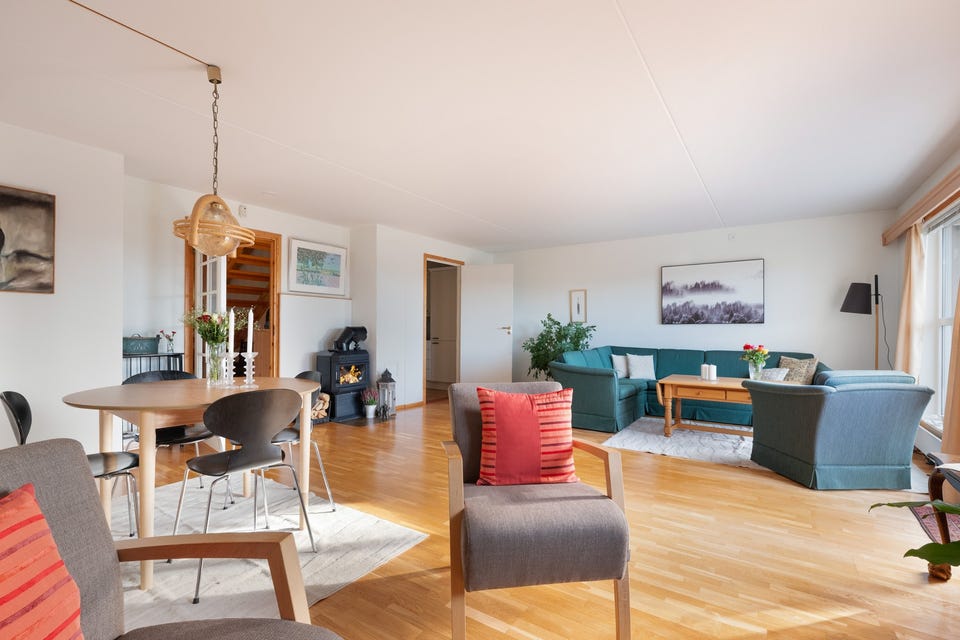 Rommet har en åpen og luftig utforming med god plass til både sofagruppe og spisebord.